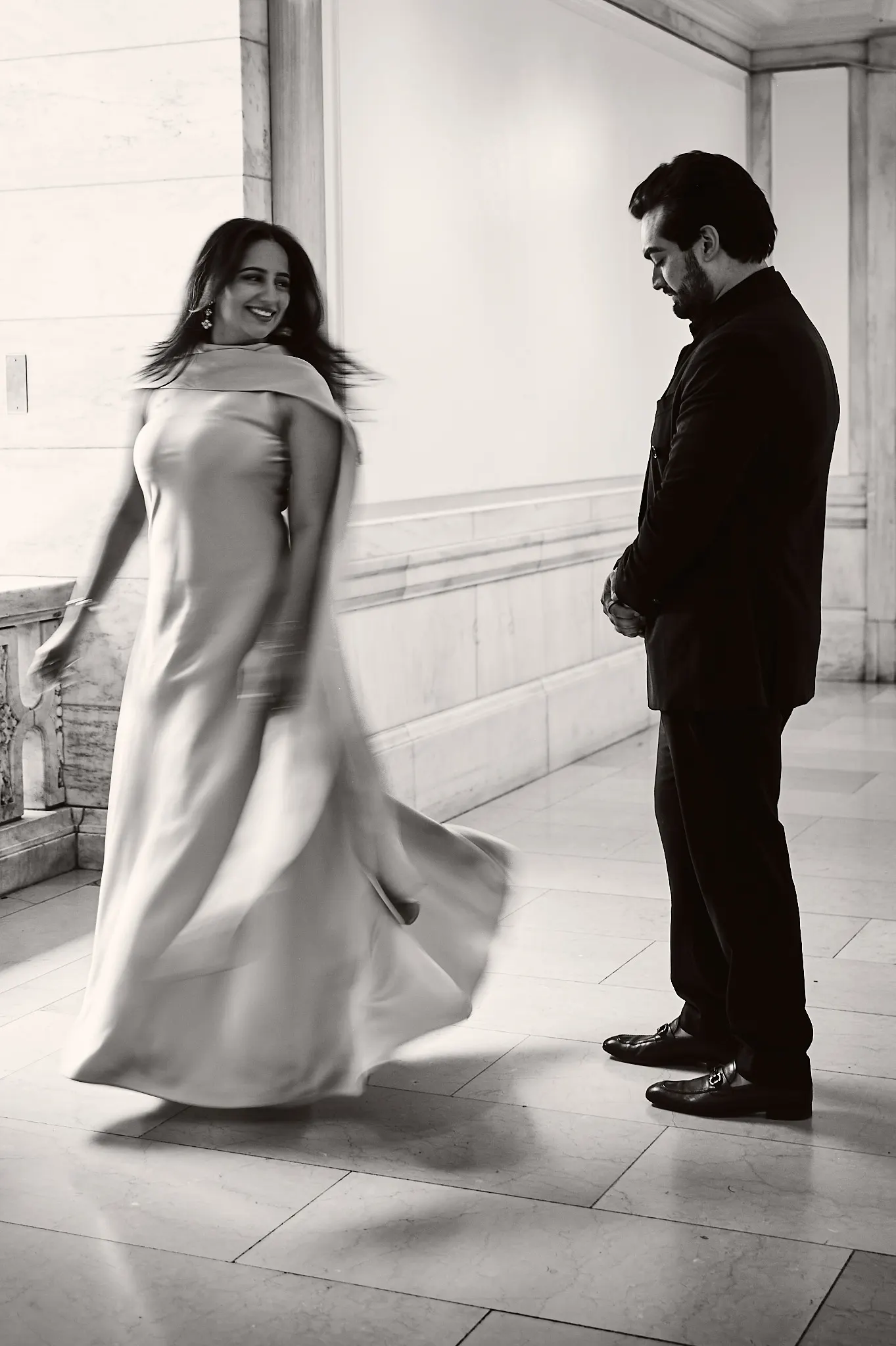 Black and white first look in marble library hall, gown blurred in motion