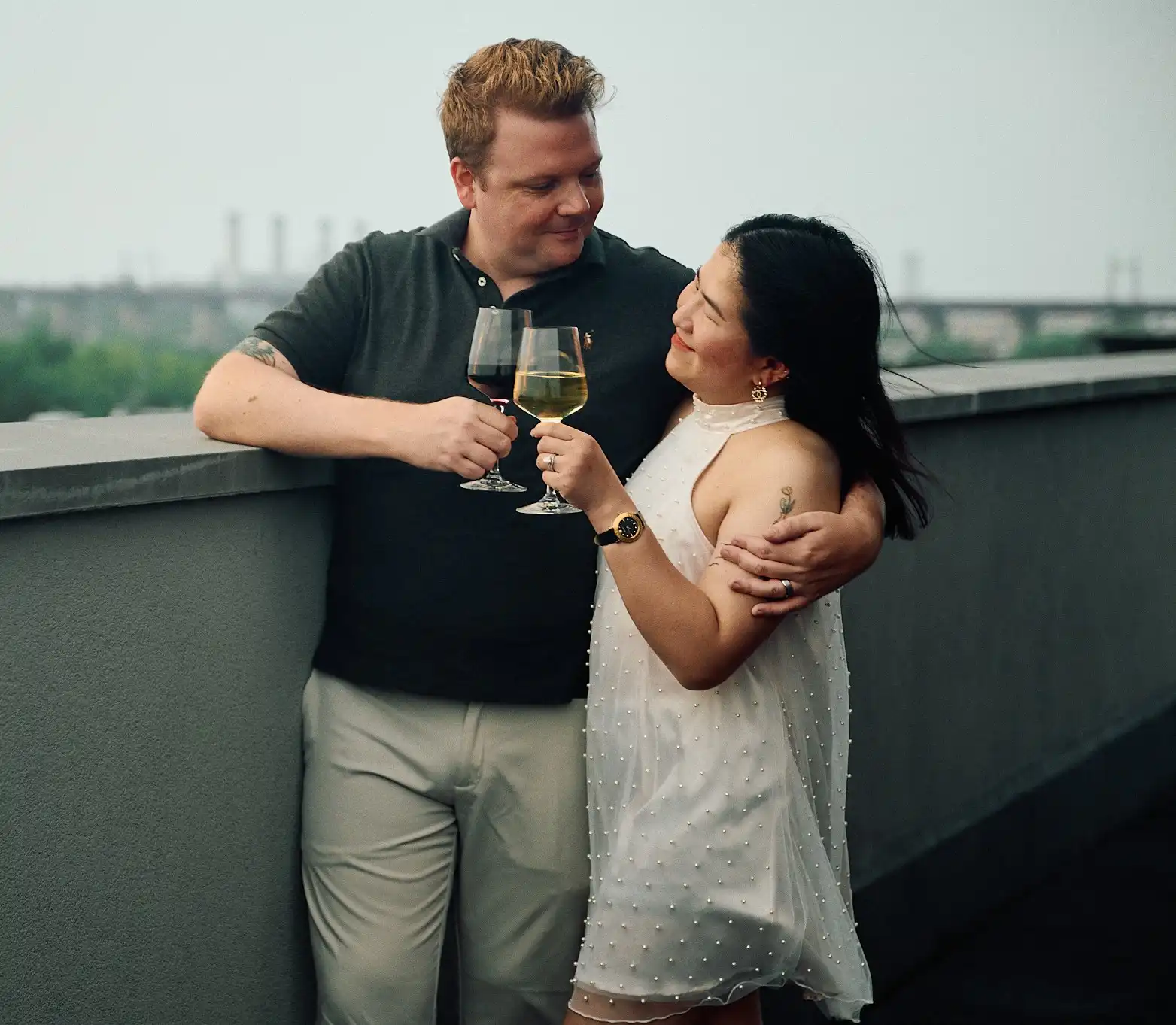 Couple slow dancing in golden light with the RFK Bridge and East River behind